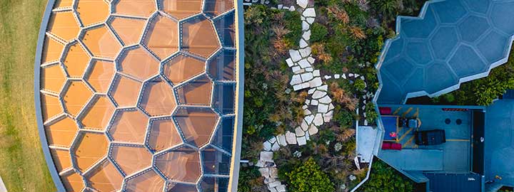An aerial view of Home of the Arts, a cultural center in Gold Coast, Australia. The roof of the center blends into a lush, planted landscape.